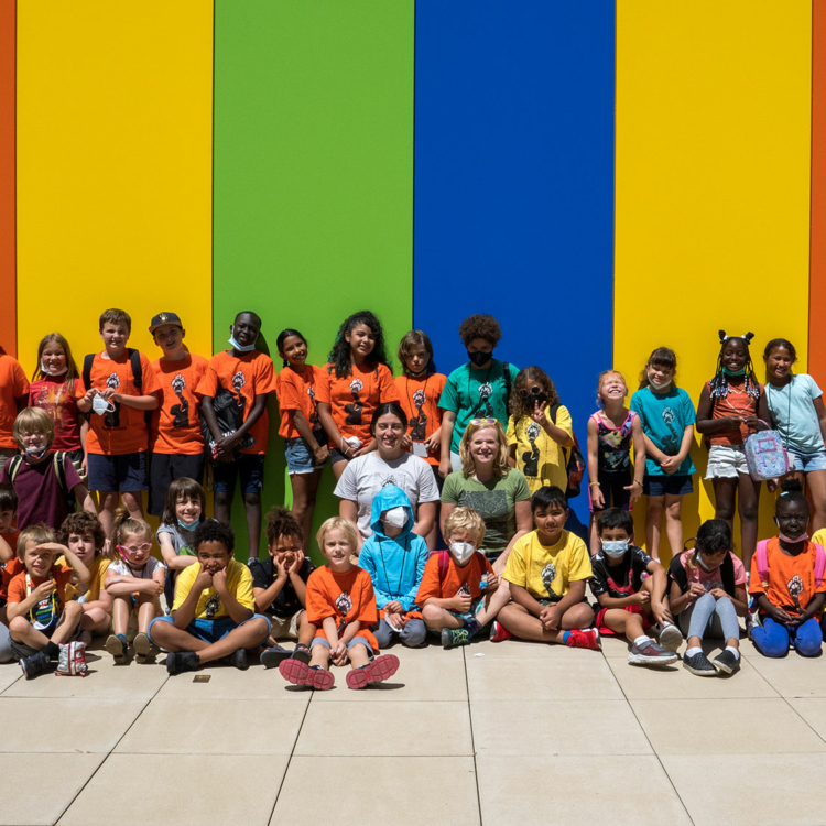 Drum Power members posing in front of a multi-colored wall at the Madison Youth Arts center