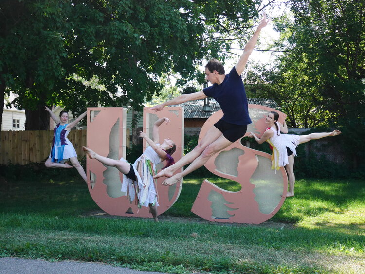 Isthmus Dance Collective members performing in front of the word US