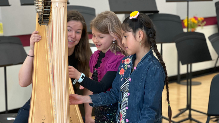 Kids examining a harp at the Madison Youth Arts center