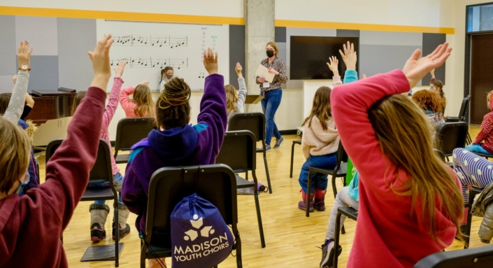 Kids raising their hands at a music lesson in the Madison Youth Arts center