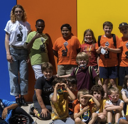 A group of kids posing together in front of a multi-colored wall at the Madison Youth Arts center