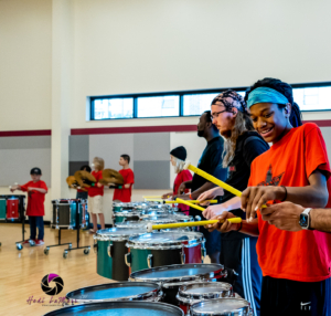Photo of Black Start Drum Line activity: several people of different ages and skin tones playing drums. 